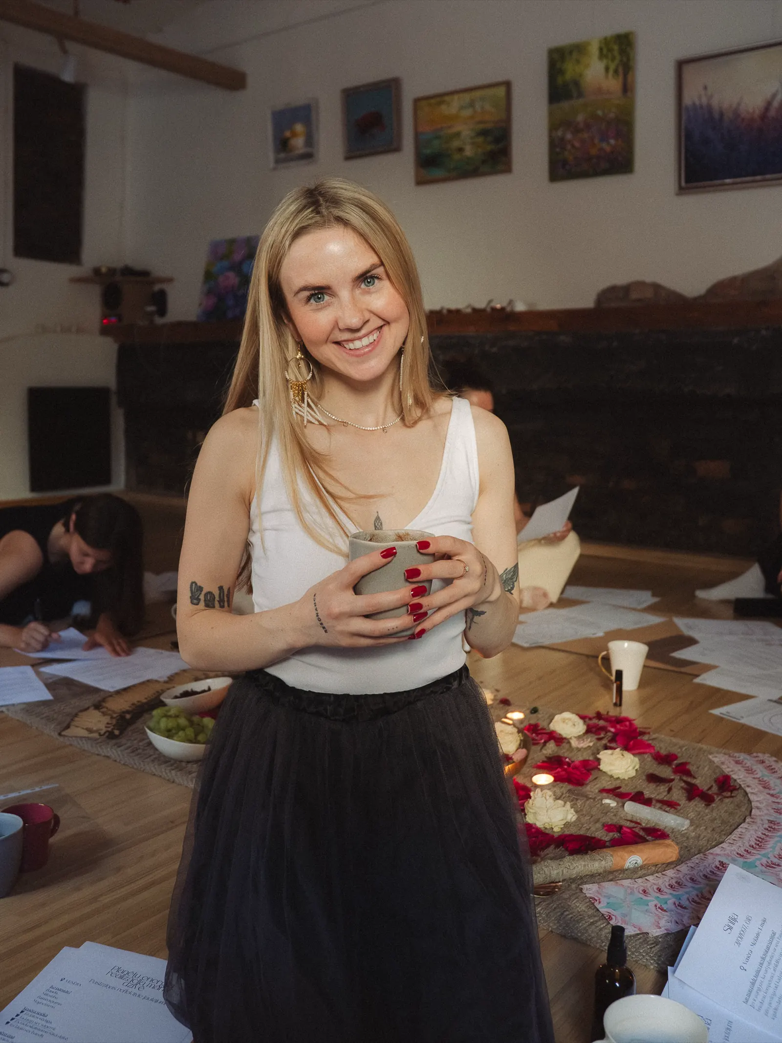 Sintija Kaui holding a cup in a ritual workshop space.